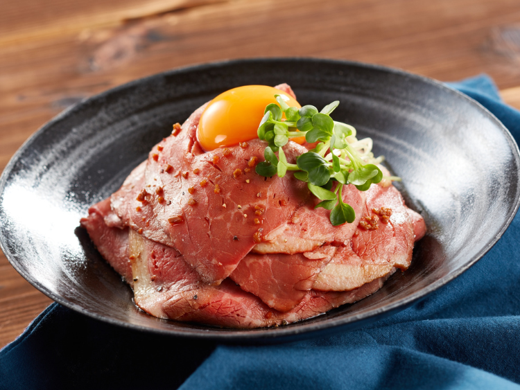 Protein-packed beef slices topped with raw egg yolk and fresh microgreens, a high-protein, low-carb gourmet dish highlighting the vibrant taste of microgreens