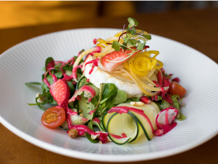 colorful-garden-salad-with-zucchini-ribbons-goat-cheese-cherry-tomatoes-pomegranate-and-microgreens-on-white-plate