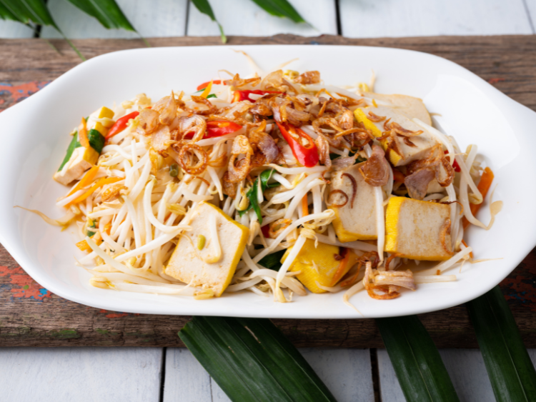 Stir-fried bean sprouts with golden tofu, sliced red chilies, scallions, and crispy shallots served on a white plate — a healthy Asian vegetable stir-fry dish.