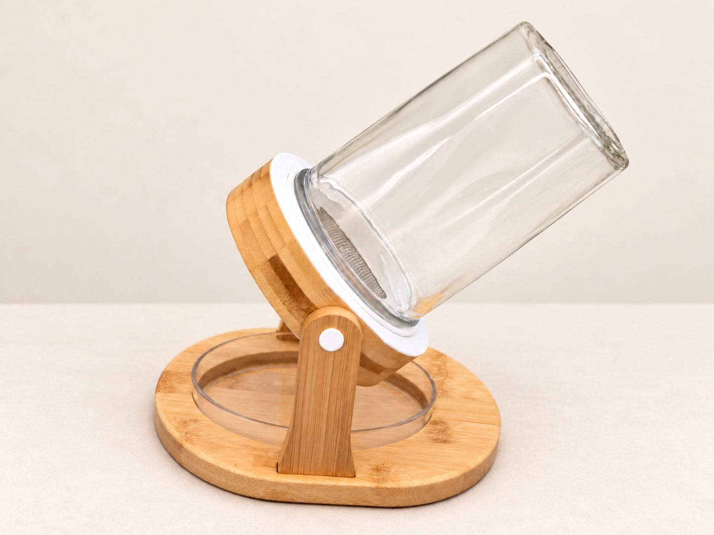 The empty jar held at an angle in the bamboo ring, above the clear oval tray in the bamboo base